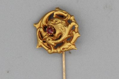 une broche en or ornée d'une pierre rouge au centre