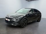 Une voiture noire est garée dans une grande pièce au sol noir.