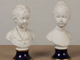 pair of white porcelain busts of a boy and a girl on black bases
