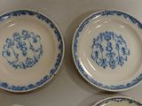 three blue and white plates with a monogram on them on a table