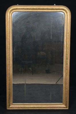 un miroir ancien dans un cadre doré sur fond noir, avec une chaise et une table en arrière-plan