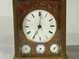a small brass clock with roman numerals on the face