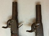 pair of old guns on a table with a white background