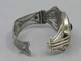silver bracelet with black stones on it on a white surface