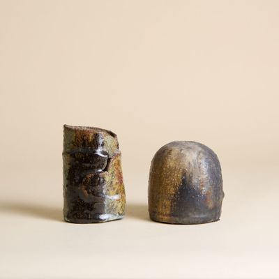 une paire de petits vases en céramique posés sur une surface blanche avec un fond beige