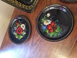 three plates with flowers painted on them sitting on a table