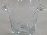 a clear glass vase with a handle on a table