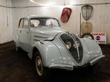 une vieille voiture dans un garage, avec une pancarte accrochée au mur