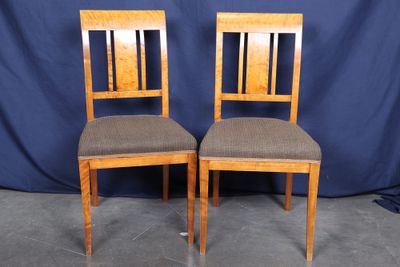 a pair of wooden chairs with brown upholstered seats