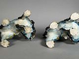 two figurines of a dog on a gray surface
