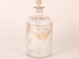 a clear glass bottle with a gold leaf design on the top