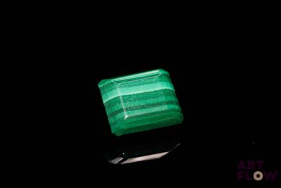 a close up of a green stone on a black surface