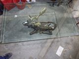 une table en verre sur laquelle se trouve un cerf en bronze