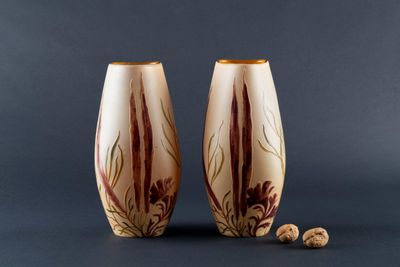 pair of hand painted vases sitting on top of a table