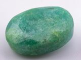 an image of a green stone sitting on top of a white surface