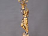 a gold statue of a woman holding a candelabra