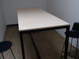 des tables et des chaises dans une pièce avec un parquet et des murs blancs