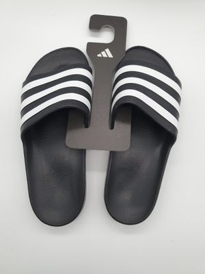 des pantoufles Adidas noires et blanches ornées de bandes blanches