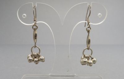 une paire de boucles d'oreilles plaquées argent sur un support en acrylique transparent