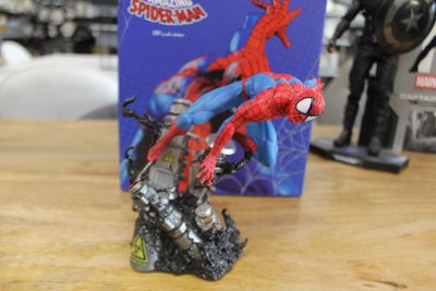 a spider - man figurine sitting on a table next to a box of toys