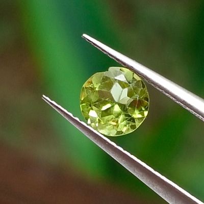 a close up of a yellow diamond being held by a pair of pliers
