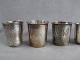 four silver cups are lined up in a row on a gray surface