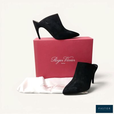 une paire de chaussures à talons hauts noires posée sur une boîte rose