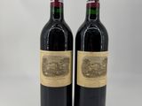 two bottles of red wine sitting next to each other on a white surface