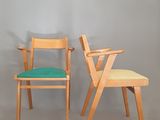 deux chaises en bois avec des coussins verts sont placées côte à côte contre un mur gris