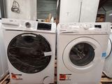 two washers and a dryer sitting on a pallet in a warehouse