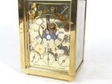 a gold clock that is sitting on a white surface