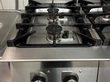 une plaque de cuisson en acier inoxydable dans une cuisine, sur laquelle sont posées des casseroles et des poêles