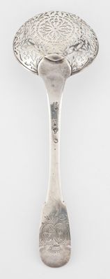 an antique silver plate with a spoon on it on a white surface