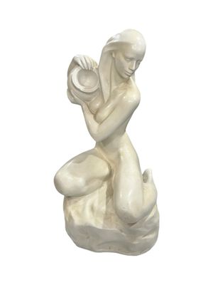 statue of a woman sitting on a rock with a shell in her hand