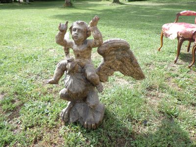 a statue of an angel sitting on a rock in the grass