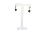 the black pearl earrings are on display on a white stand