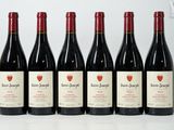 six bottles of red wine are lined up on a white surface