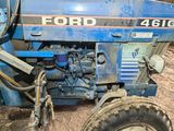 a blue tractor that is parked in the dirt