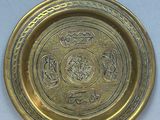 a close up of a brass plate on a wooden table