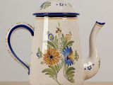 une théière blanche ornée de fleurs bleues et jaunes