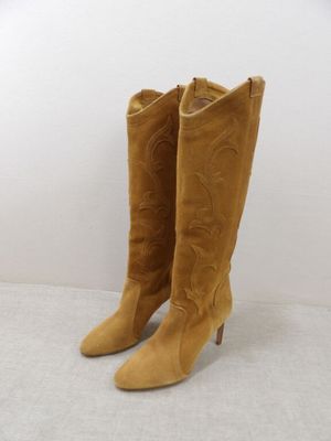 pair of tan sued cowboy boots on a white surface