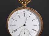 a gold pocket watch with roman numerals on the face