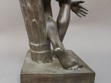 une statue en bronze représentant un homme tenant une souche d'arbre