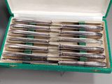 a lot of silverware in a green box on a table