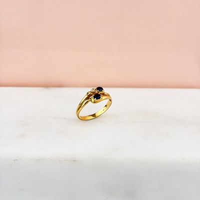 une bague en or sertie d'un diamant noir, posée sur une dalle de marbre