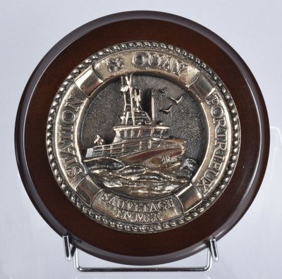 a silver plate with a ship on it on a stand