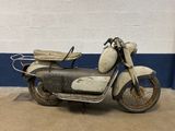 an old moped parked in front of a white wall
