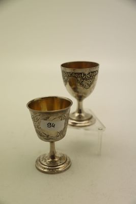 deux gobelets en argent posés sur une table blanche
