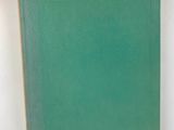 a green book sitting on top of a table next to a white wall