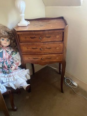 une poupée assise sur une chaise devant une commode